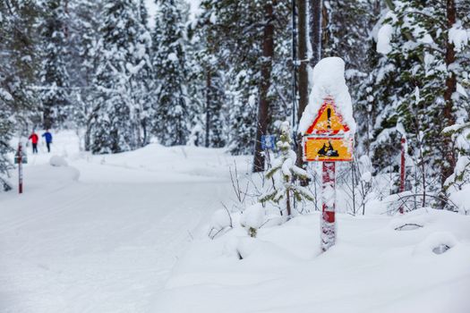 Warning traffic sign, warning skier sign on snowy arctic winter forest.