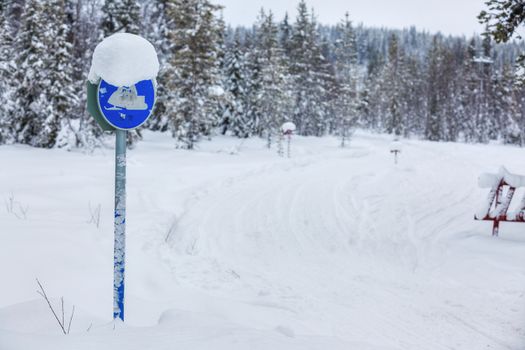 Warning traffic sign, warning snowmobile sign on snowy arctic winter forest.