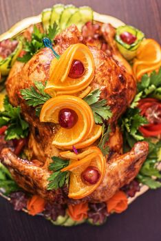 Whole roasted chicken with vegetables and fruits on wooden table