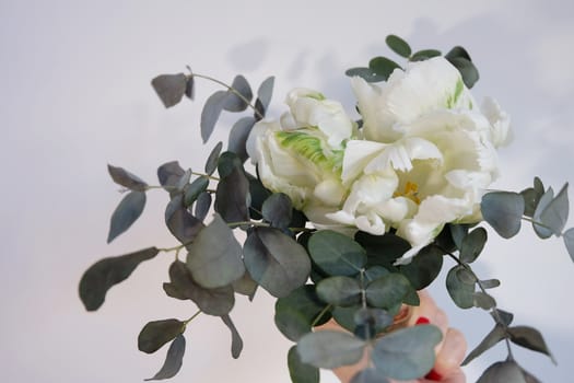 Bouquet of white parrot tulips and eucalyptus in a vase