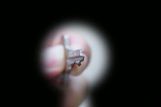 Key in hand prepares to open in keyhole, close up, isolated on black background