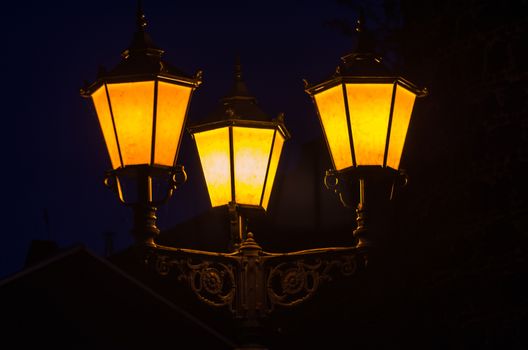 Candelabra, street lamp, three lamps lit at night.