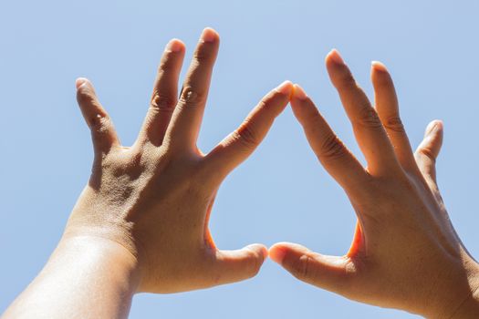 Girl hand in upside down heart form love blue sky.