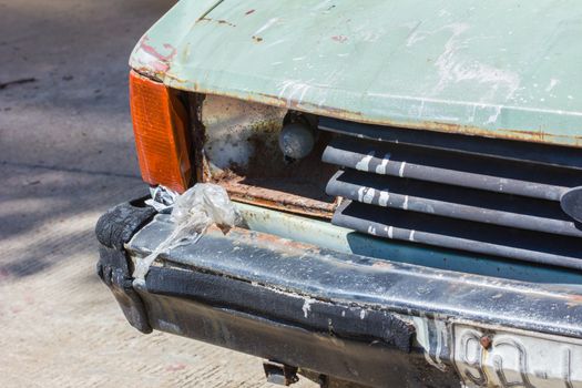 Close up shot of a junked car left in a car park.
