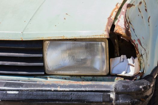 Close up shot of a junked car left in a car park.