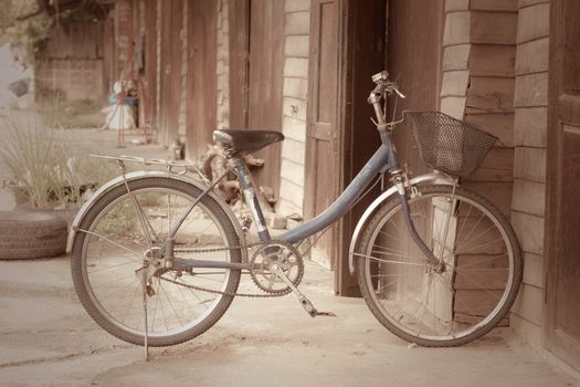 Old bike in front of the wooden wall at home.