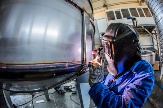 Man welding with reflection of sparks on visor. Hard job. Construction and manufacturing