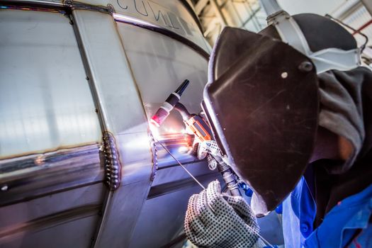 Man welding with reflection of sparks on visor. Hard job. Construction and manufacturing
