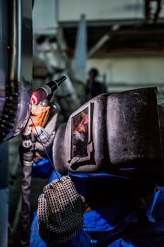 Man welding with reflection of sparks on visor. Hard job. Construction and manufacturing