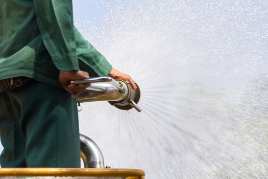 man watering plants on water truck in the park, closeup