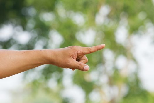Human hand point with finger in green background with bokeh.