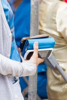 woman holding one purse and two mobile phone in her hand.