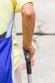 Old woman hand leans on walking stick, close-up
