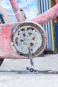 old chain wheel of bicycle with dry mud .