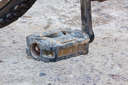 Detail of old used bicycle pedal with dry mud .