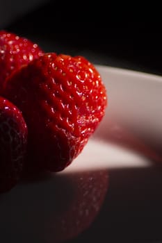 Strawberries on black background. Bright deep red.