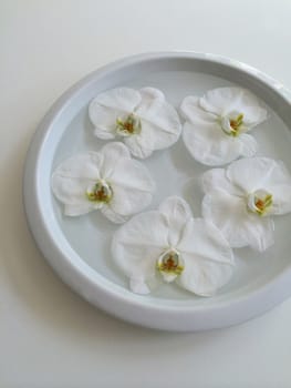Five floating orchids in a bowl of water