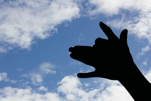 dog shape hand silhouette in blue sky.
