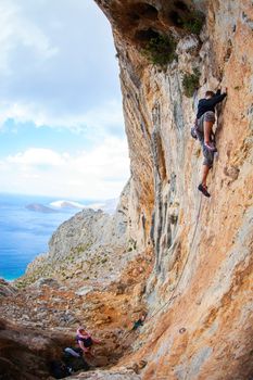 Young man lead climbing on cliff near sea, Kalymnos island, Greece