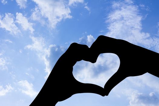 love shape hand silhouette in blue sky.