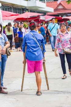 CHIANGRAI, THAILAND - AUG 12: unidentified young disable woman waking in the crowd with crutches on August 12, 2014 in Chiangrai, Thailand.