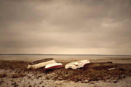 Image textured softly with sandstone texture of boats on shore in sparse colors.
