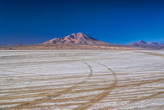 Wheel tracks in desert covered by white salt in Salar de Uyuni in Bolivia