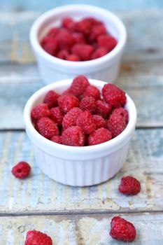 much fresh ripe raspberry in a white bowl on a wooden background
