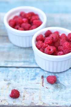 much fresh ripe raspberry in a white bowl on a wooden background