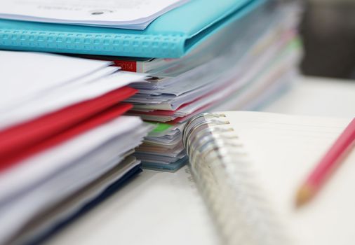 Piles of papers and files are placed on the desk in the office.                               