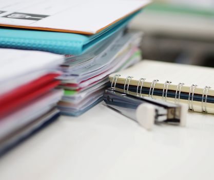 Piles of papers and files are placed on the desk in the office.                             