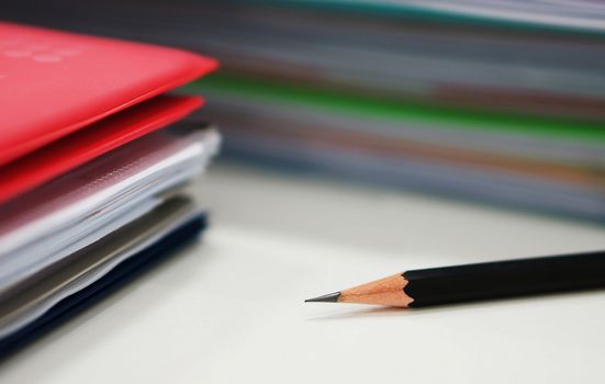 Pencil and many piles of document on desk at office.                             