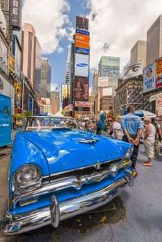 NEW YORK CITY - JUNE 12, 2013: Vintage car in Times Square on a beautiful day with curious tourists.