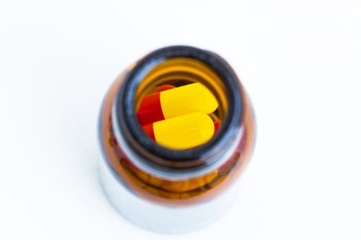 yellow red capsules  in a bottle, shallow depth of field, focusing on capsules