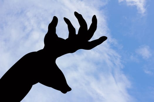 deer and horn shape hand silhouette in blue sky and cloud, with copyspace 