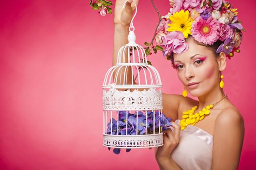Young skin care model is holding a bird cage with flowers