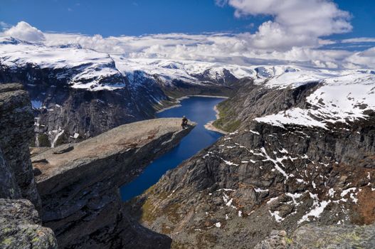 Hiker sitting at the edge of Trolltunga rock daydreaming 