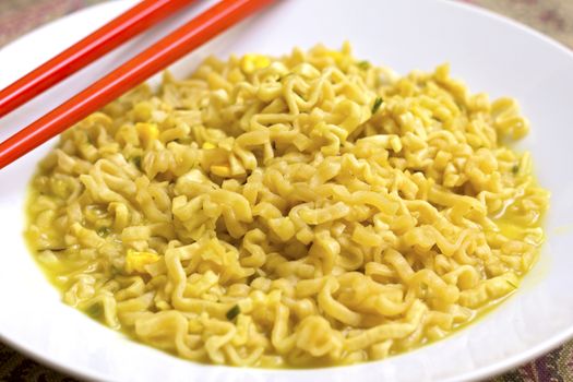 A dish of chicken noodles with red chopsticks