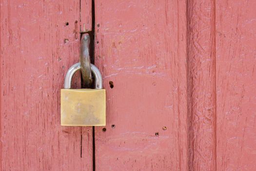 closeup of lock on the middle of pale red wood door, copyspace on the right