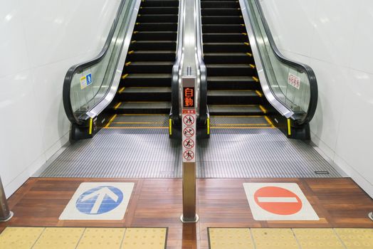 an escalator upstair way and downstair way with sign on the floor