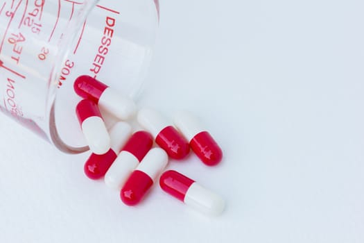 group of white red  capsule medicine in glass on white background.