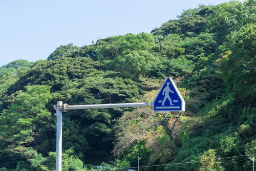 The symbol sign for the people to across the street which natural background of mountain