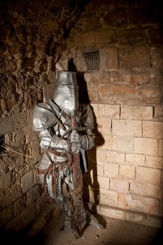 imprisoned medieval knight in armor lit by a shaft of light