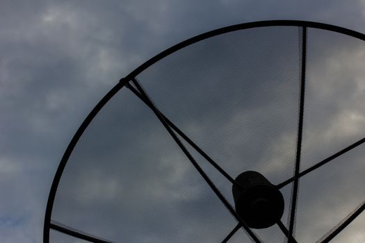 closeup of satellite dish in evening cloudy sky, silhouette.