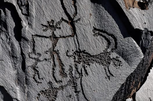 Ancient petroglyphs engraved on rock on Saimaluu Tash site in Kyrgyzstan