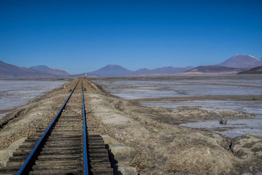 Rail tracks in desert covered by white salt in Salar de Uyuni in Bolivia