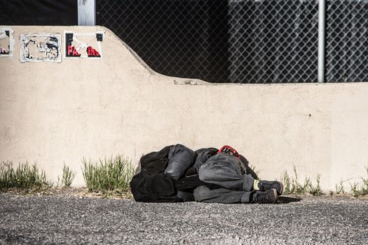 Homeless person sleeping near wall in parking lot