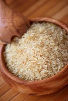 golden rice on wooden plate on wooden background