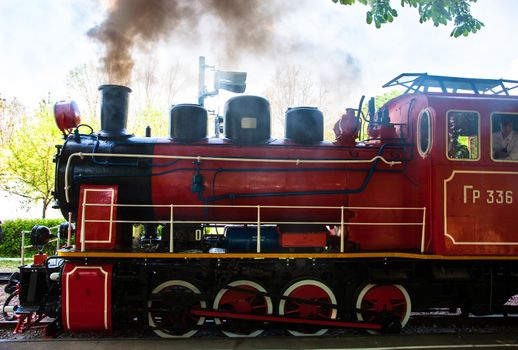 Steam locomotive with the smoke blowing off out of the smokestack.