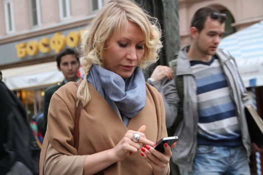 Moscow, Russia - on May 27, 2012. After disputable elections the opposition organized many protest actions on streets of Moscow. This meeting - public political club in the fresh air on Stary Arbat Street at a monument to the poet Okudzhava. The politician Alyona Popova looks in the smartphone